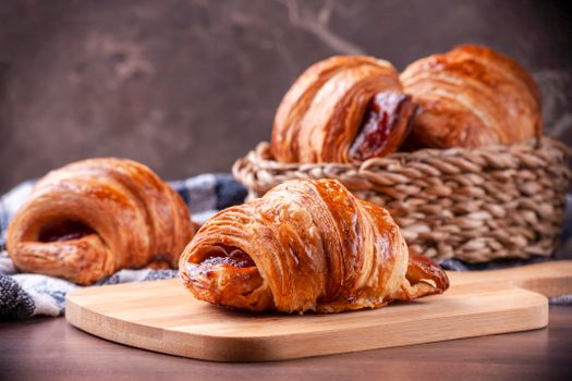 Close-up photo of freshly baked croissants on a wooden board, placed artistically in a basket.