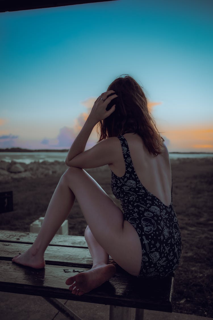 Woman In Swimsuit Sitting On Bench On Beach