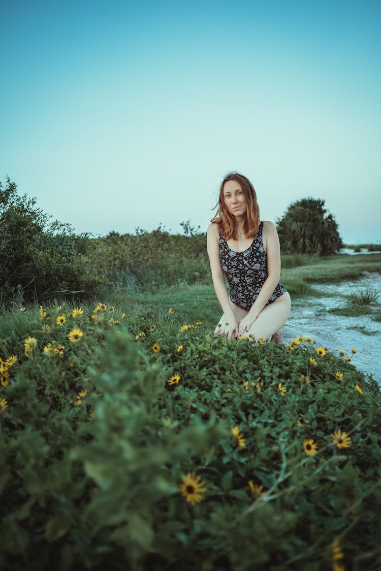 Woman In Swimsuit Sitting At Green River Bank