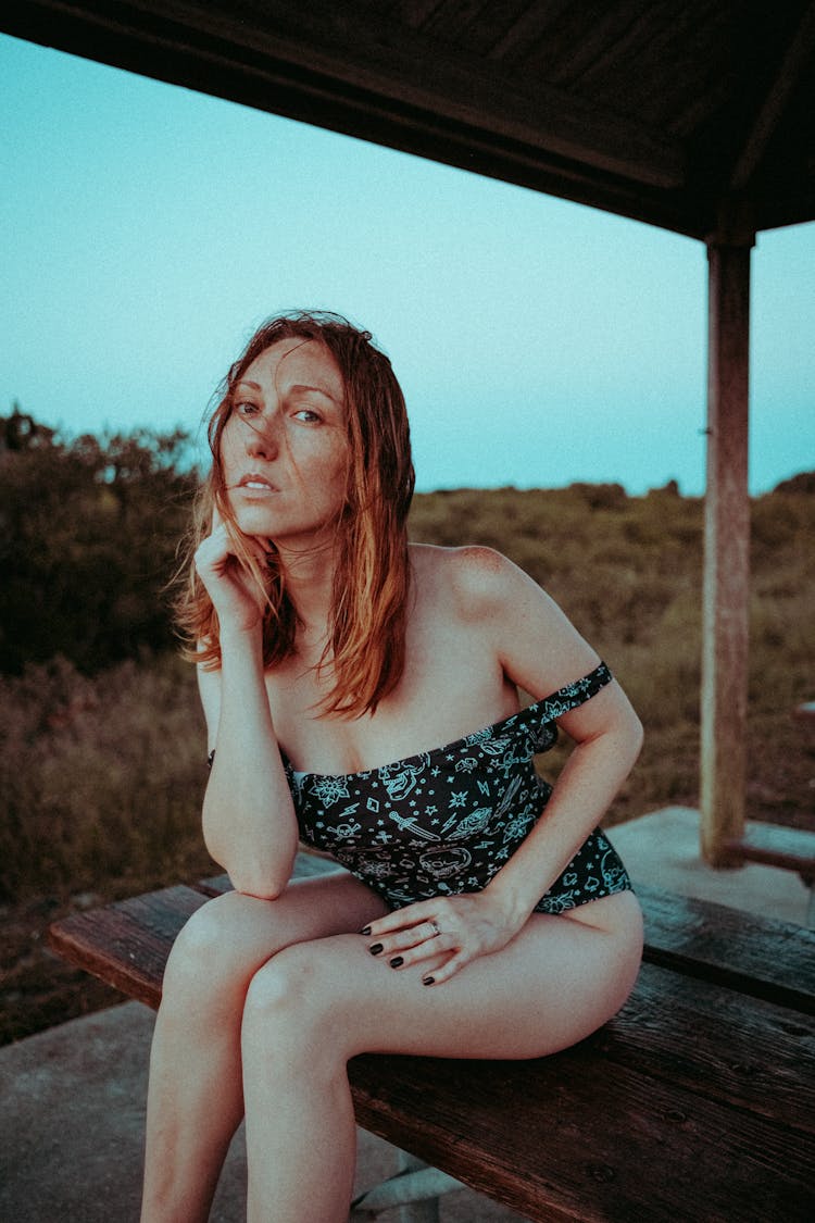 Woman In Swimsuit Sitting On Bench On Beach