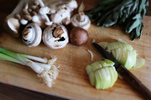 Vegetables Mushrooms and Knife on Wooden Board