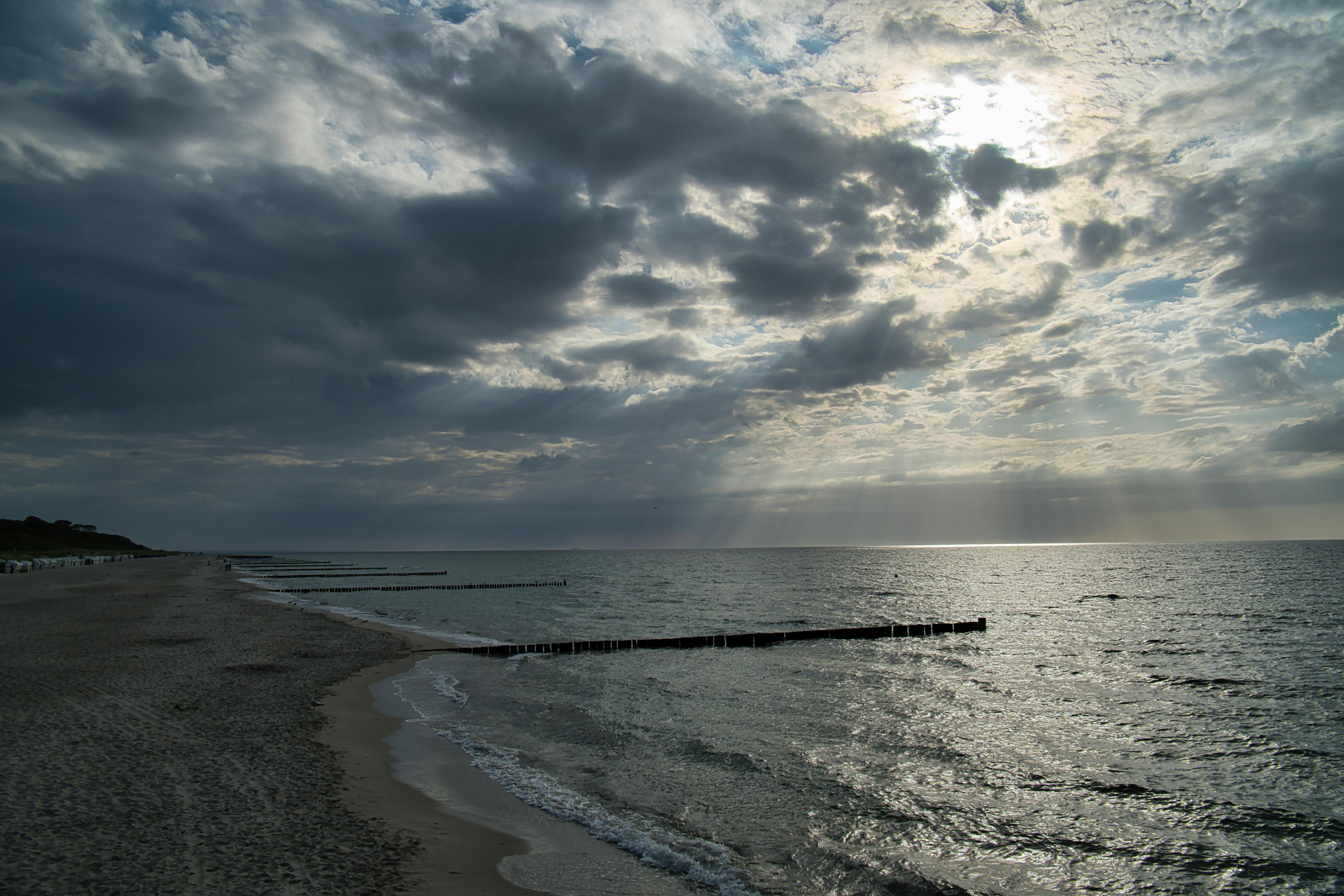 A scenic view of the ocean at Wustrow Beach, Germany with dramatic clouds and sunlight.