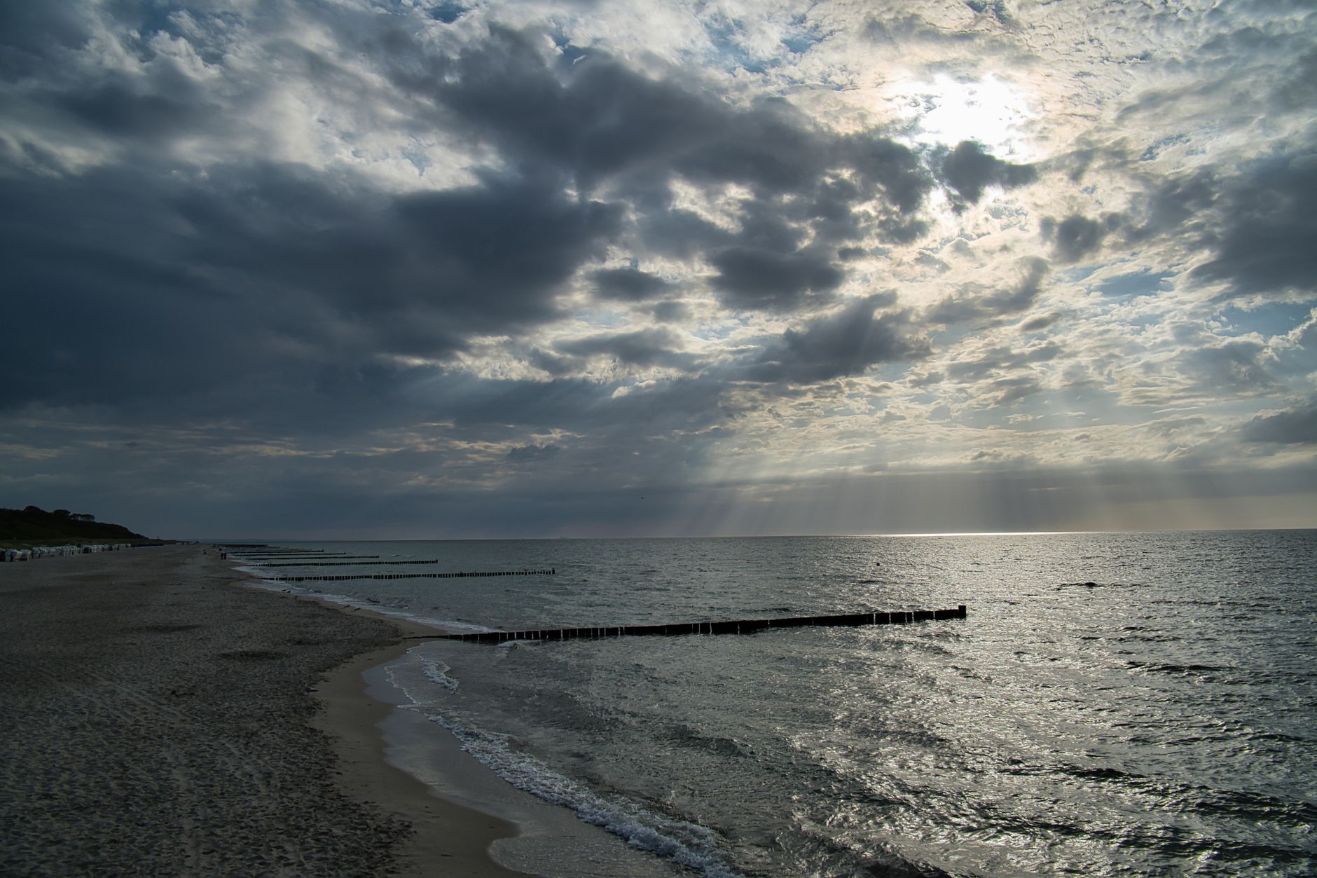 A scenic view of the ocean at Wustrow Beach, Germany with dramatic clouds and sunlight.