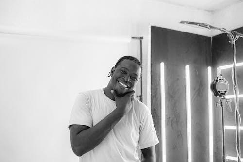 Man in Crew Neck T-shirt Smiling in Grayscale Photography 