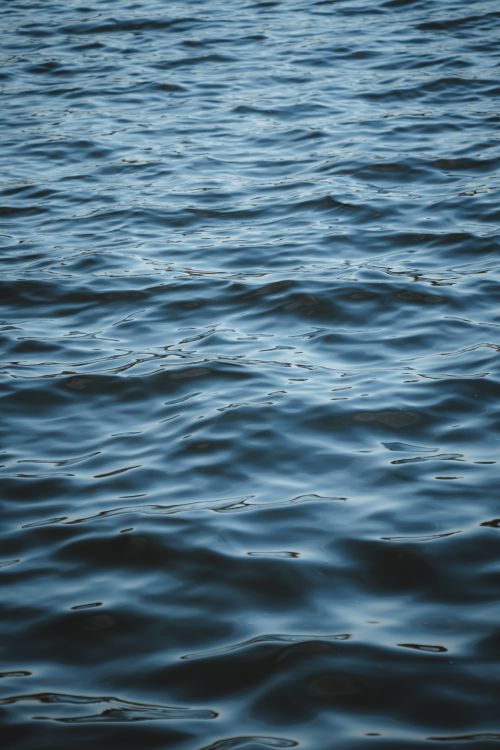 Free A close-up view of rippling water creating abstract wave patterns. Stock Photo