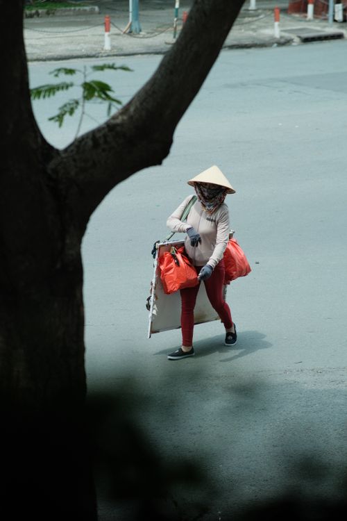 Free A street vendor carrying bags in a city while wearing a traditional conical hat. Stock Photo