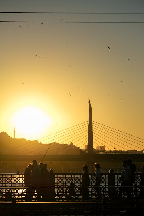 Silhouette of People Walking Near Golden Horn Metro Bridge during Sunset