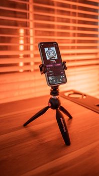 Smartphone mounted on a tripod playing music indoors with warm ambiance.