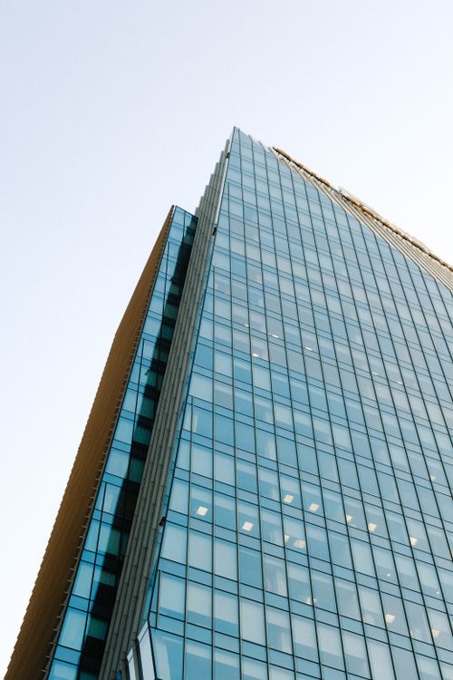 Free Low angle view of a modern glass skyscraper exterior against a clear sky. Stock Photo