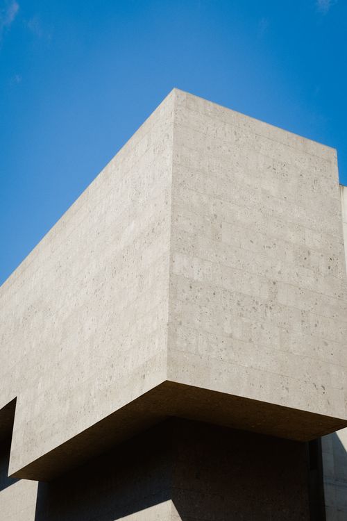 Free A striking concrete building facade captured against a clear blue sky, showcasing modern architectural design. Stock Photo