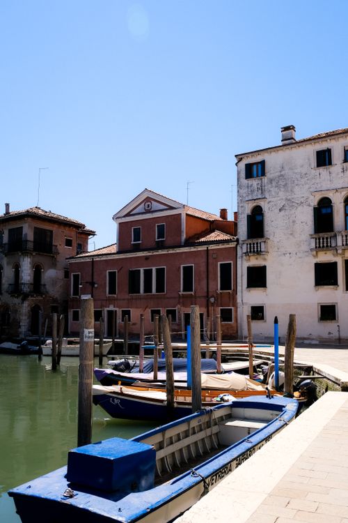 Free Charming Venice canal view with docked gondolas and historic architecture under clear blue skies. Stock Photo