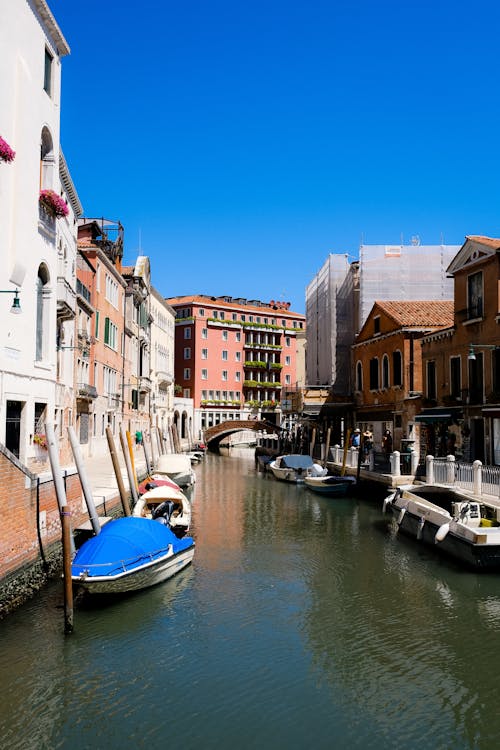 Blue and White Boats in the River Between Buildings