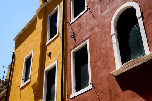 Free A vibrant Mediterranean building with yellow and red walls under a clear blue sky captured from a low angle. Stock Photo