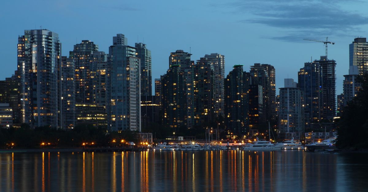 Stunning view of Vancouver's illuminated skyline reflecting on calm waters at dusk.