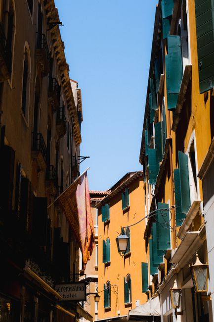 Discover a sunlit street in Venice, showcasing colorful Italian architecture and charm.