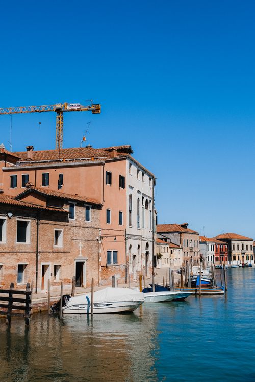 Free Scenic view of boats along a Venetian canal lined with historic architecture under a clear blue sky. Stock Photo