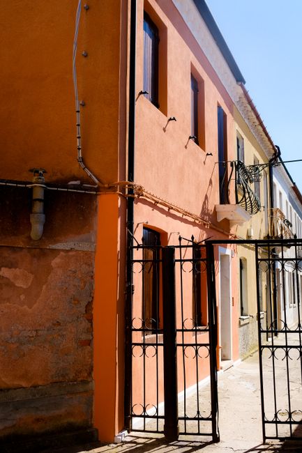 Charming alley with vibrant buildings and iron gate under bright daylight.