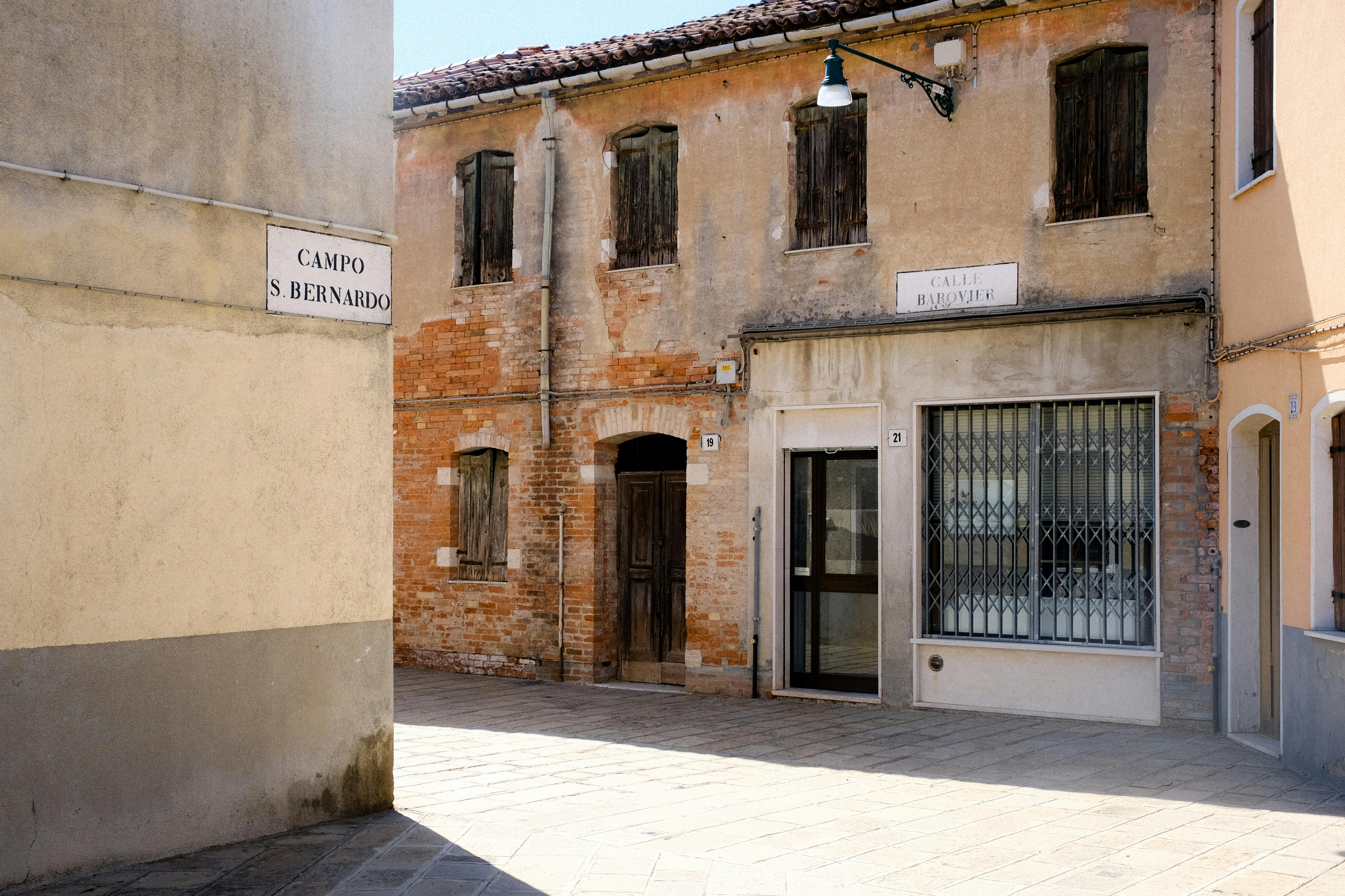 Abandoned townhouse in a quiet street with rustic facade and shutters, perfect for architectural exploration.
