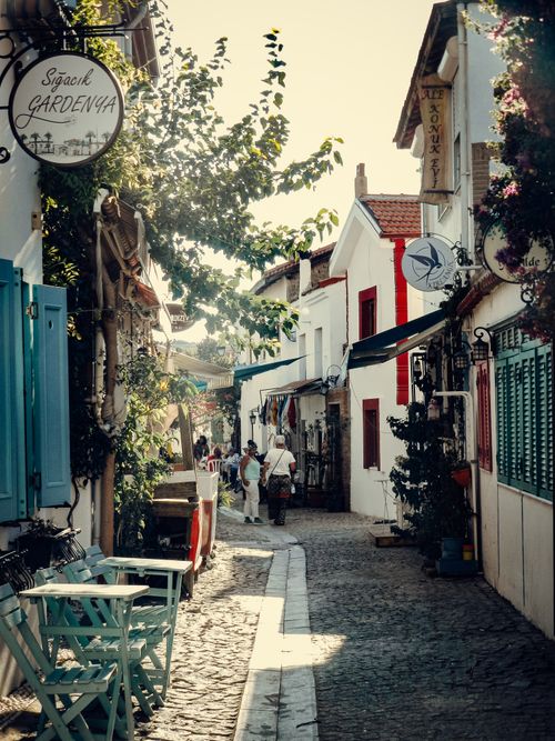 Free Sunlit cobblestone alley with vintage shop signs in a picturesque European village, inviting exploration. Stock Photo
