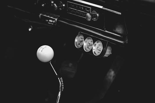 Black and white photo of a vintage car gear shift with a retro dashboard.