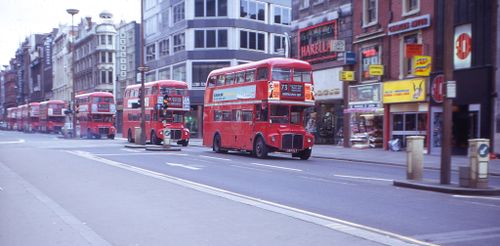 Free A row of iconic red double-decker buses on a busy city street. Stock Photo