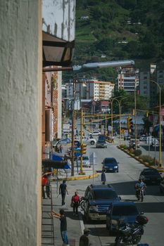 Vibrant urban street in Venezuela showcasing daily city life with cars and pedestrians.