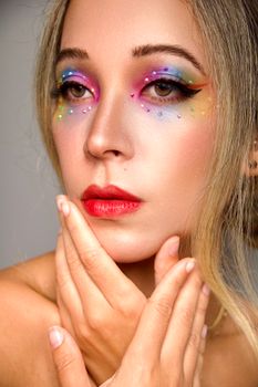 Vibrant close-up portrait of a woman with colorful artistic makeup and gemstones.