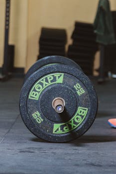 Close-up of a 10kg gym dumbbell resting on an indoor gym floor, highlighting fitness equipment.