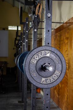 Close-up of a barbell setup in a gym with equipment and industrial lighting.