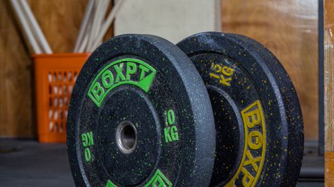 Heavy weight plates stacked in a rugged gym, ready for training.