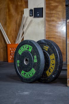 Heavy weight plates stacked in a rugged gym, ready for training.