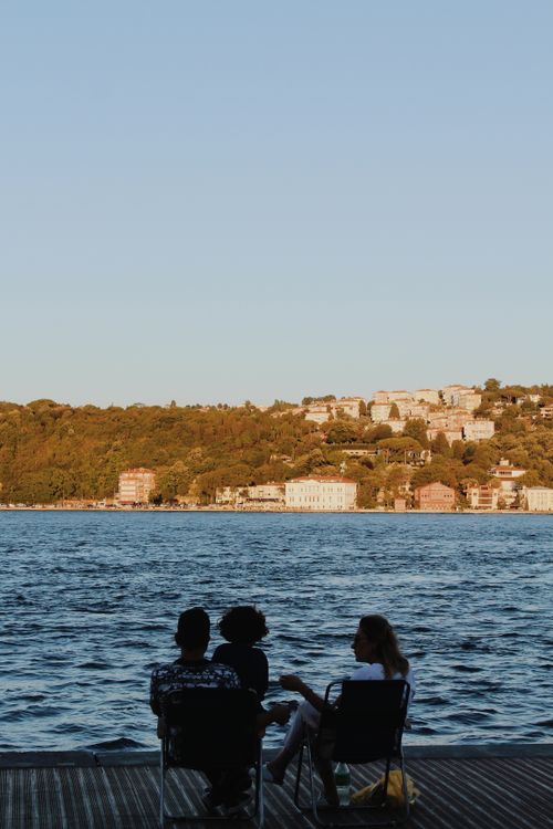 Free Friends enjoy the sunset by the Bosphorus in Istanbul, featuring a peaceful waterfront view. Stock Photo