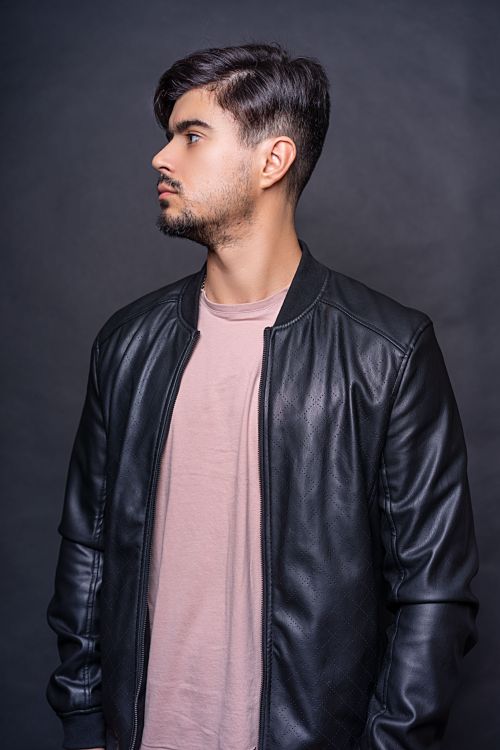 Free Young man in a leather jacket looking to the side on a grey background. Stock Photo