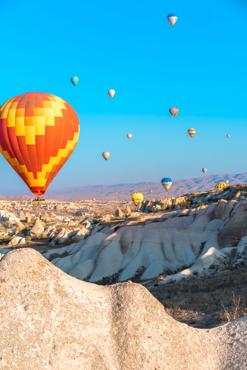 Free Vibrant hot air balloons float over the stunning fairy chimneys in Cappadocia, Turkey. Stock Photo