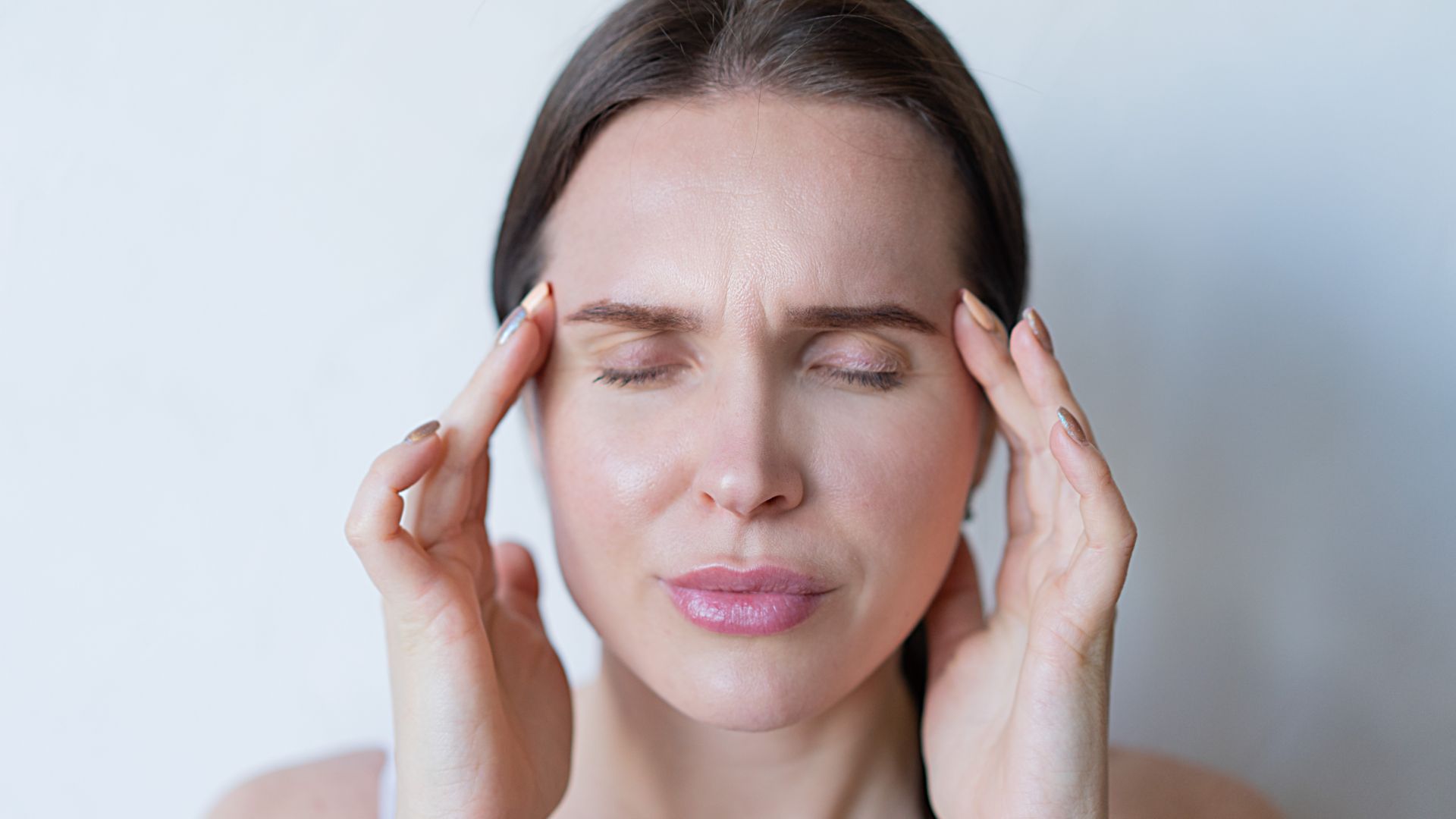 modafinil headache: Guide Close-up of a woman with closed eyes holding her temples, showing signs of a migraine or headache — modafinil headache