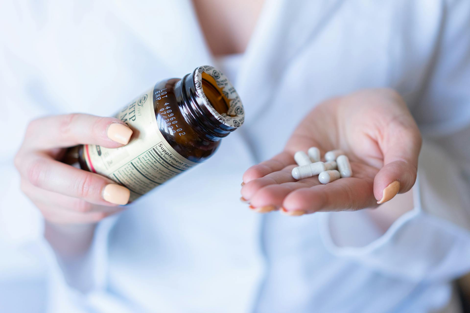 A close-up shot of hands holding a medicine bottle and pills, with a focus on healthcare and medication usage.