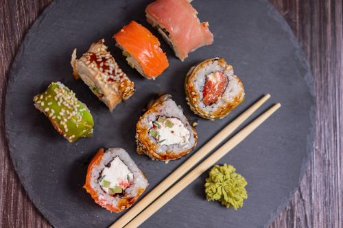 Free Close-up of assorted sushi rolls on a black slate plate with chopsticks and wasabi. Stock Photo