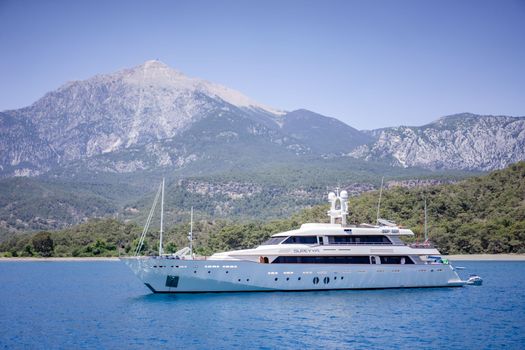 A sleek yacht sailing in front of majestic mountains in Kemer, Antalya, Turkey.