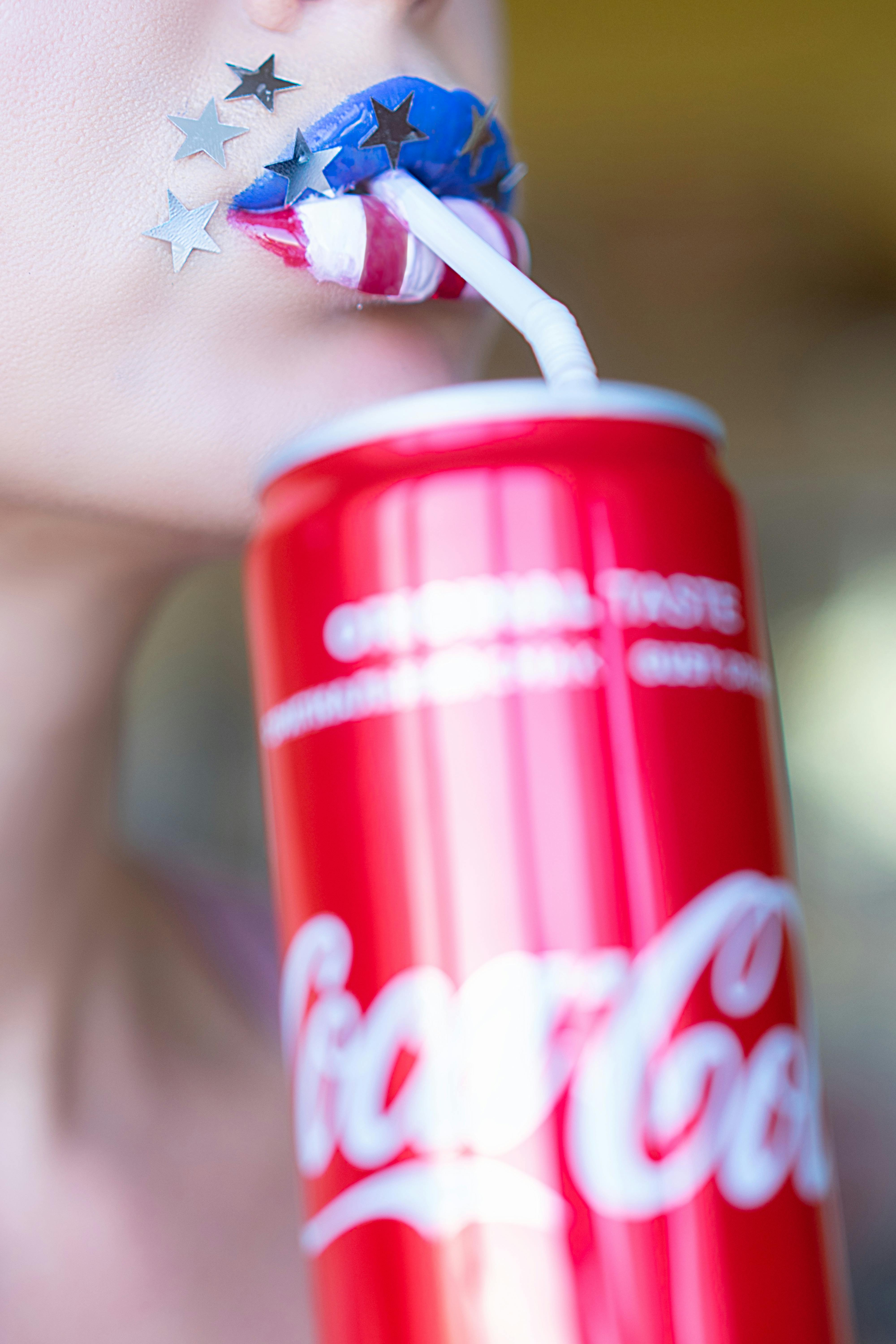Patriotic lip art with a soda can and straw in a creative close-up.
