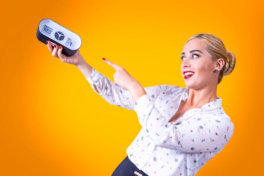 Cheerful woman pointing at a modern alarm clock on an orange background.