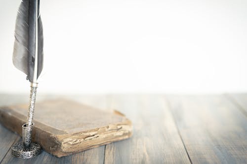 Old Book and Quill Pen on Wooden Table