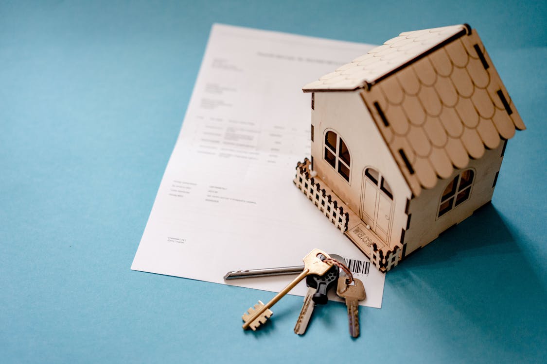 Keys and a miniature house placed on a piece of paper.