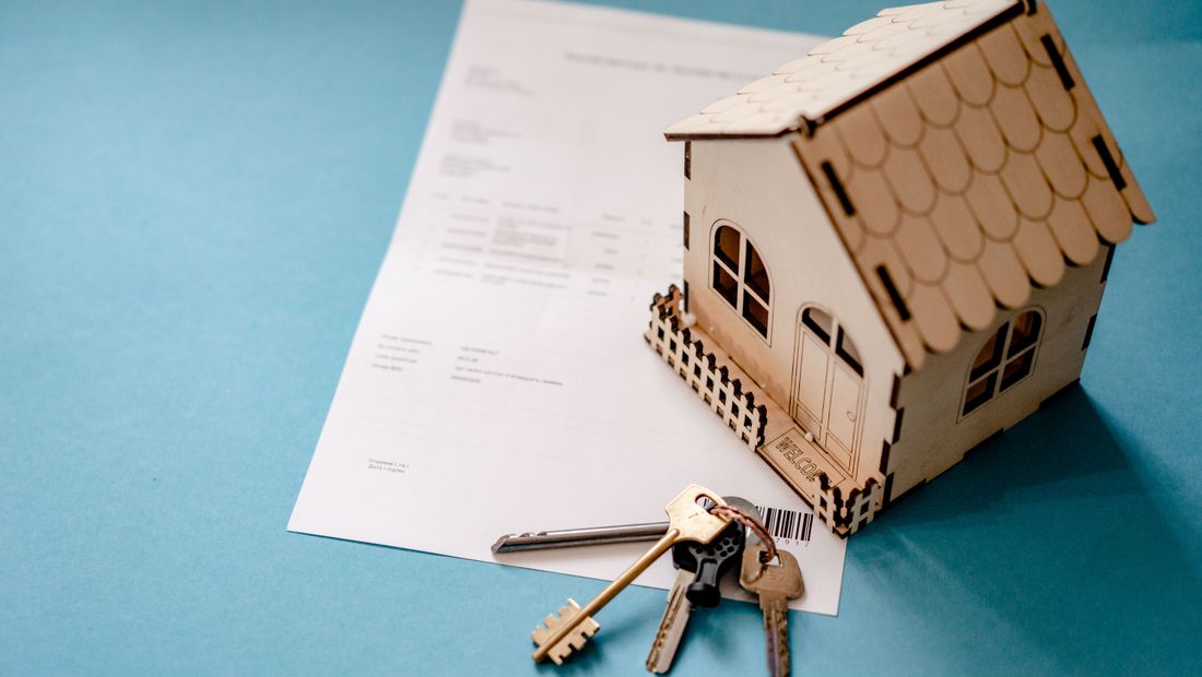 Maquette de maison, clés et contrat de transaction sur un bureau