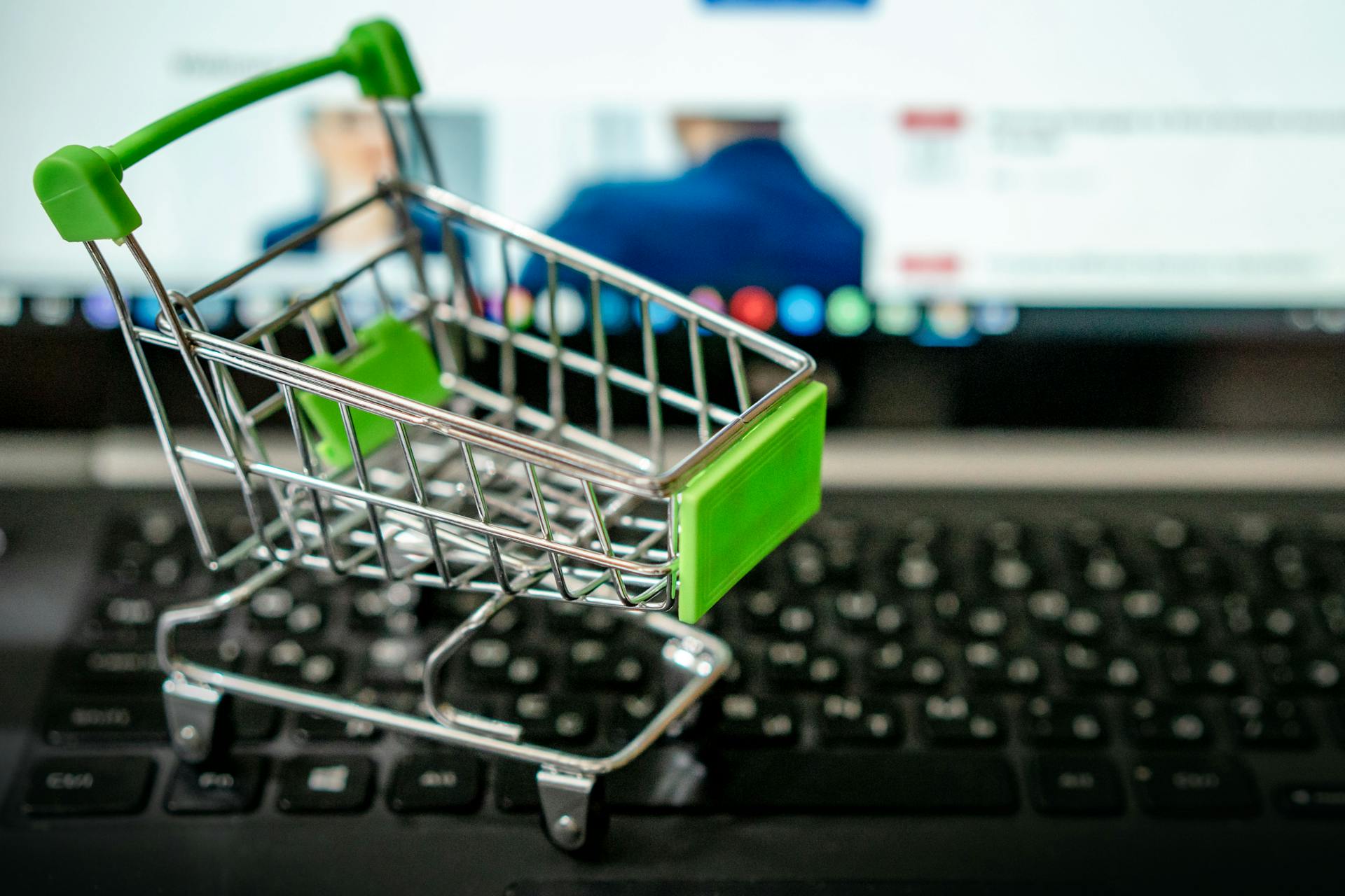 Miniature shopping cart placed on a laptop keyboard, symbolizing online shopping.