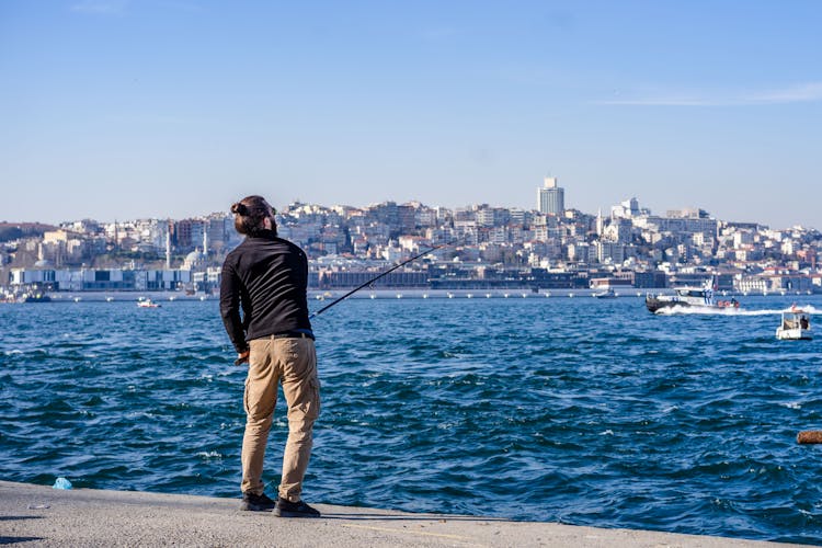 A Person In Black Long Sleeve Shirt And Brown Pants Fishing  