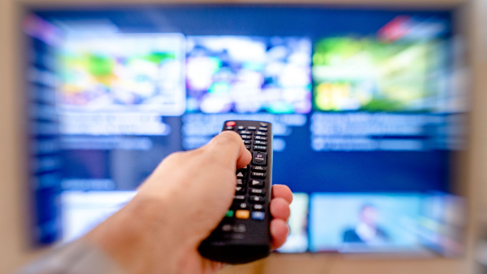 A television remote control being used in front of a home television