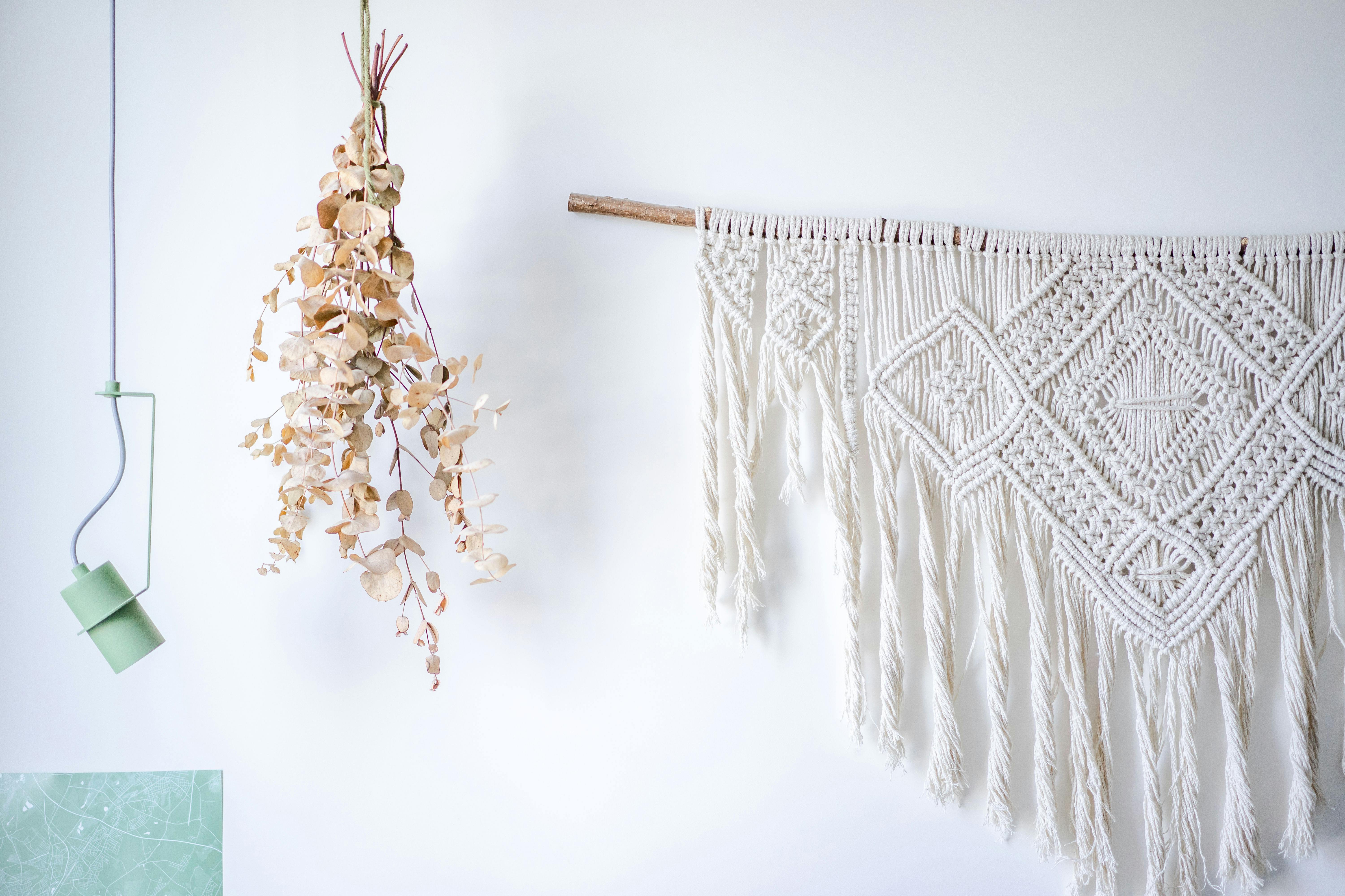 A stylish macrame wall decoration with dried eucalyptus and modern lighting.