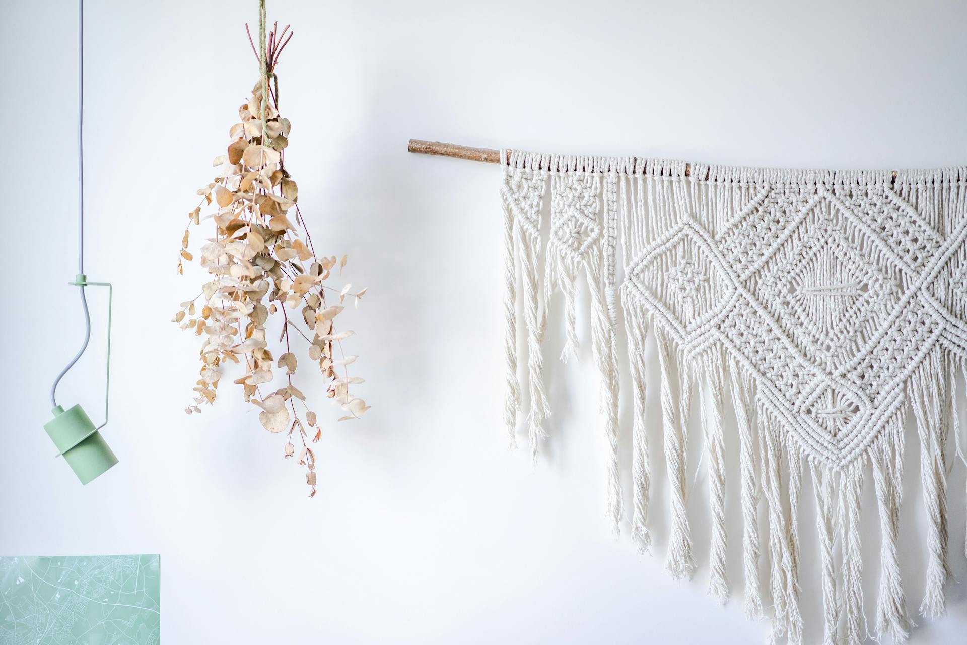 A stylish macrame wall decoration with dried eucalyptus and modern lighting.