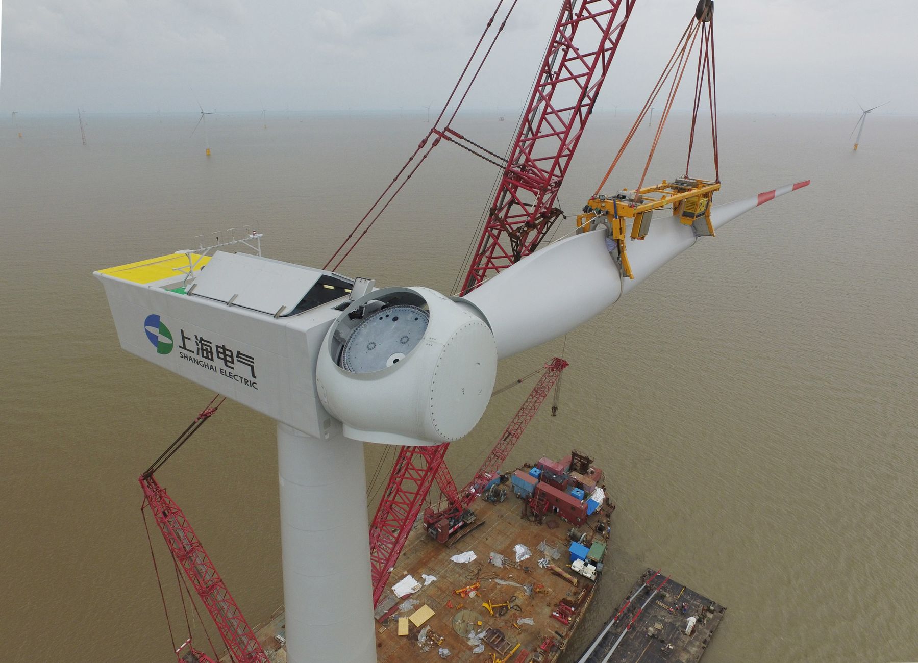 Aerial view of a wind turbine being installed over the sea, showcasing renewable energy construction.