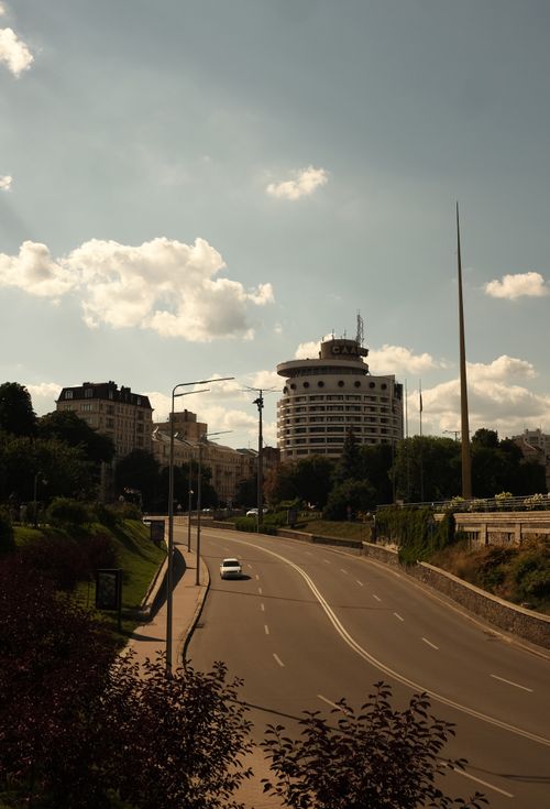 Free Scenic view of a historical hotel and spire in Kyiv with clear skies and traffic-free road. Stock Photo